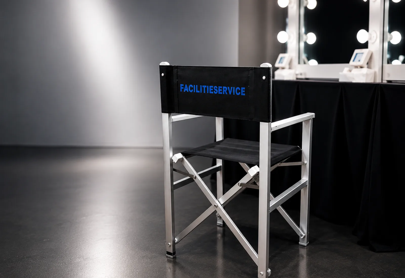 Sedia regia brandizzata Facilitieservice davanti a una postazione trucco illuminata nel backstage